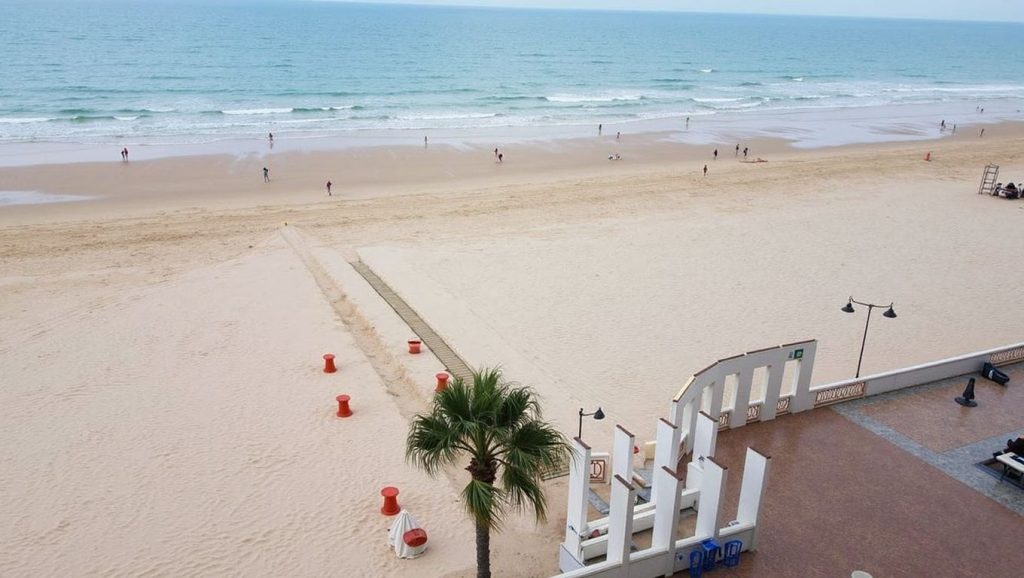 Orilla de Playa La Victoria con olas suaves en Cádiz